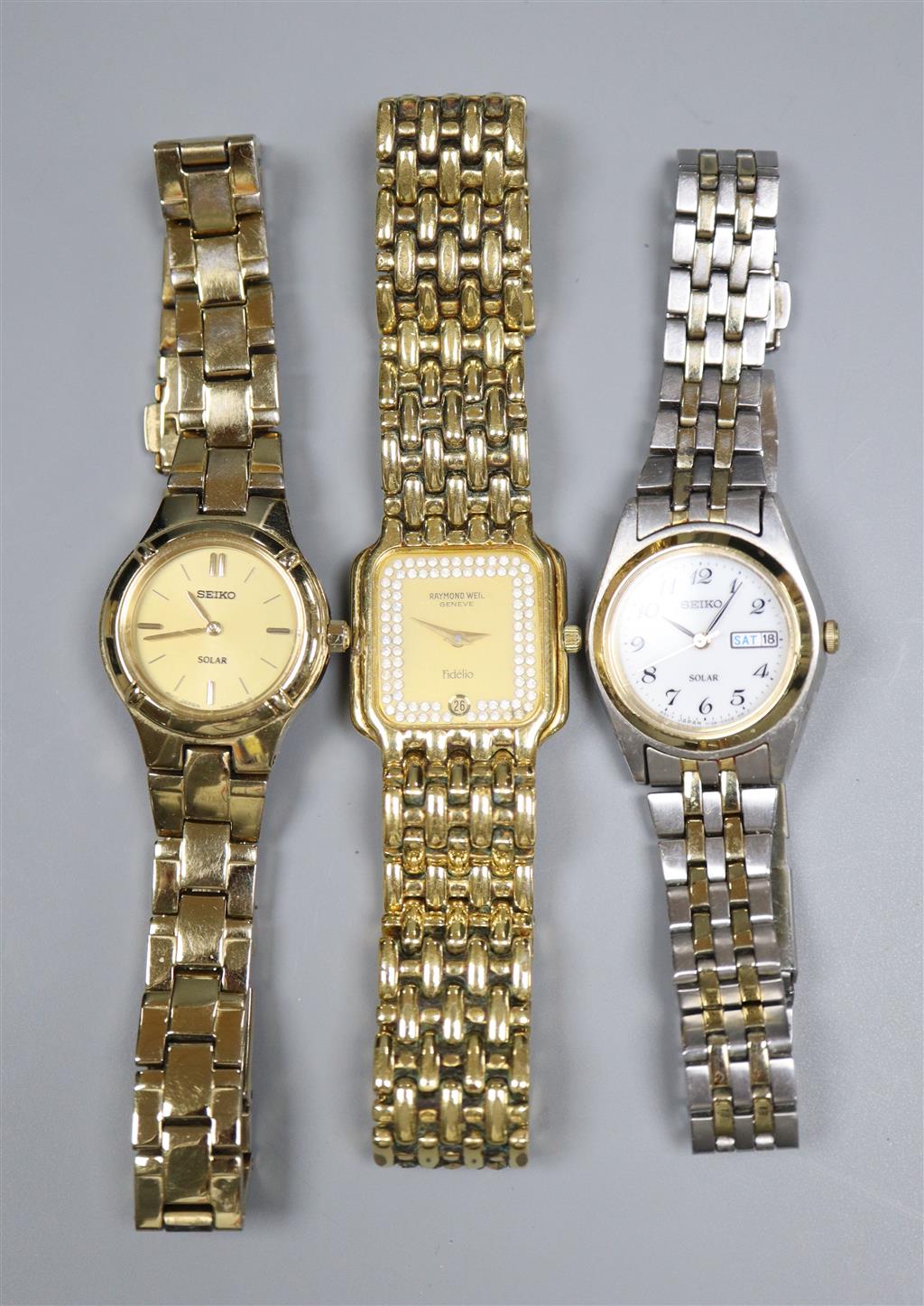 A ladys Raymond Weil gilt metal wrist watch and two Seiko wrist watches.